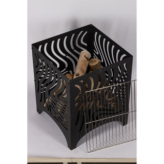 Das Bild zeigt eine schwarze Metall-Feuerschale mit dekorativen Ausschnitten in einem wellenförmigen Muster. Neben der Feuerschale befindet sich ein abnehmbarer Metall-Grillrost, der zum Kochen über dem Feuer gedacht ist. Die Feuerschale hat eine offene Oberseite und steht auf vier Beinen._von oben