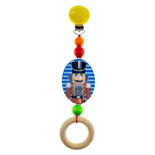 Greifling aus Holz mit gelben Clipverschluss, einem farbig bedruckten Nussknacker und einem Greifring in natur