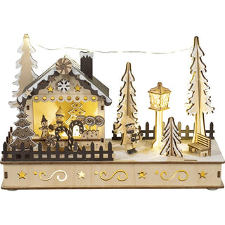 Ein hochwertig verarbeitetes LED Diorama "Weihnachtshaus" aus Holz. Am Rand eine hell erleuchtete Weihnachtsmarkthütte mit allerlei Naschereien im Angebot. Davor eine gedrechselte Kinderfigur mit einem Weihnachtsgeschenk in den Händen. Auch die Laterne ist mit einer LED Beleuchtung ausgestattet.&nbsp; Zwischen den Tannen leuchtet eine Lichterkette._1