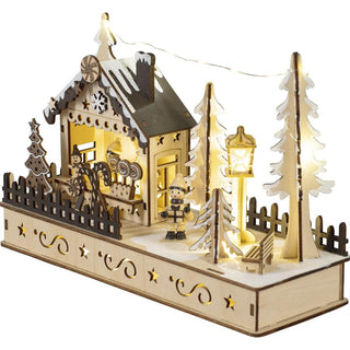 Ein hochwertig verarbeitetes LED Diorama "Weihnachtshaus" aus Holz. Am Rand eine hell erleuchtete Weihnachtsmarkthütte mit allerlei Naschereien im Angebot. Davor eine gedrechselte Kinderfigur mit einem Weihnachtsgeschenk in den Händen. Auch die Laterne ist mit einer LED Beleuchtung ausgestattet.&nbsp; Zwischen den Tannen leuchtet eine Lichterkette._3