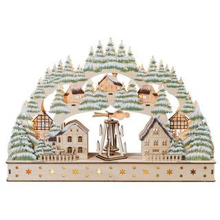 LED Lichterbogen Dorf mit bewegl. Pyramide. Auf dem Bogen ist ein Dorf abgebildet. In der Mitte des Dorfplatztes befindet sich die bewegliche Pyramide. Umrandet ist der Bogen mit Grünen, beschneiten Bäumchen. Der Sockel wird duche das durchbrochene Sternenmotiv auch beleuchtet.