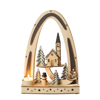 LED-Lichterbogen aus Holz auf einem Sockel mit Sternen, einer Kirche, Bäumchen, Schneemann, Winterkind auf Schlitten und einer Halterung für ein Teelicht. 