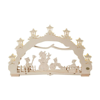 Dieser 7-flammige Schwibbogen in Natur ist ein verspieltes Sammlerstück, original hergestellt im Erzgebirge. Winterkinder bauen mit viel Freude einen Schneemann. Ein Kind bringt noch den Besen, ein anderer Spielkamerad rollt schon die nächste Kugel. Vielleicht für eine Schneefrau?  Das 3. Kind fährt mit seinem Schlitten um das Gelände. Die indirekt beleuchteten Laternen um den Bogen erhellen die dunkle Winterzeit besonders auch in Ihrem Fenster.