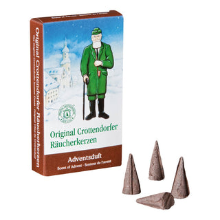 Verpackung der Original Crottendorfer Räucherkerzen mit dem Duft ‚Adventsduft‘. Die rechteckige Schachtel ist in Blau und Braun gestaltet. Auf der Vorderseite ist eine Illustration eines Mannes in grüner Kleidung mit Spazierstock vor einer winterlichen Landschaft mit Kirche zu sehen. Darunter steht ‚Original Crottendorfer Räucherkerzen‘ sowie ‚Adventsduft‘ mit den Übersetzungen ‚Scent of Advent‘ und ‚Senteur de l’avent‘.  Vor der Schachtel liegen vier braune, kegelförmige Räucherkerzen.
