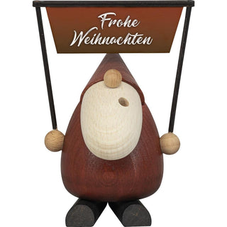 Der ca. 14cm-große wohlgeformte Weihnachtsmann aus Holz trägt ein großes Schild in der Armen mit der Aufschrift, Frohe Weihnachten. Zur Mundöffnung aus dem weißen Bart kommt der Dampf heraus. Die Stiefel sind schwarz, die Kleidung ist rot und die Nase, ein Rucksack und auch die Hände sind naturfarben. Die Figur hebt man von den Füßen ab, um eine Räucherkerze abzulegen. Damit hat man zusätzlich einen besinnlichen Weihnachtsduft im Raum. Diese Figur ist in verschiedenen Motiven erhältlich. Bild 1.