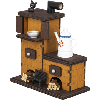 Räucherofen MassivholzDer Räucherofen aus Massivholz besteht aus 2 Ebenen. Auf der oberen Ebene sitzt eine kleine, schwarze Katze. Auf der unteren Ebene steht eine Kaffeekanne. Vor dem Ofen liegen 2 Holzstapel und in der Mitte, vor dem Ofen steht noch eine kleines Bänkchen_2