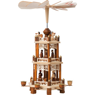 Naturfarbene Weihnachtspyramide Christi Geburt mit 2 Etagen. Auf der unteren Etage befindet sich die Szene von Christi Geburt mit Maria, Joseph und dem Jesuskind. Auch die 3 Heiligen Könige sind abgebildet. Auf der zweiten Etage sind die Kurrendesänger zu sehen. Auf der oberen, festen Etage spielt der Engelschor. Auf den Flügeln sind Weihnachtssterne aufgedruckt.