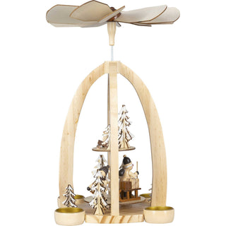 Weihnachtsyramide für 4 Teelichte mit 2 Etagen. Auf der unteren Etage sieht man den Weihnachtsmann und ein Winterkind, dass auf dem Schlitten die Geschenke zieht. Umrahmt wir ddiese Szene mit einigen beschneiten Bäumchen. Auf der oberen Etage befindet sich ein Reh und ein Winterbäumchen._2