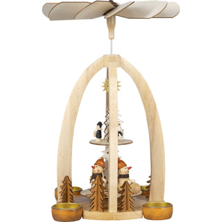 Weihnachtspyramide für 4 Teelichte und mit 2 Etagen. Auf der unteren Etage befinden sich 3 kleine Schneemänner beim Wintersport. auf der oberen Etage ist die Kurrende abgebildet und ein goldfarbener Stern ziehrt die Mitte der Pyramide._3