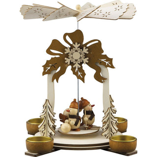 Naturfarbene Weihnachtspyramide für Teelichte. Auf der Pyramide befinden sich 3 lustige  Schneemänner beim Wintersport. Am oberen Teil den Pyramidenbogens ist ein großer Weihnachtsstern abgebildet. Die Pyramidenflügel sind mit Sternen verziert.