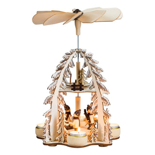 Naturfarbene Weihnachtspyramide für 4 Pyramidenteelichte und 2 Etagen. Auf der unteren Etage befindet sich die Winterinder. Auf der oberen Etage ist ein kleiner winterwal mit Zaun und Bäumchen. Die Pyramidenbögen sind aus beschneiten Tannenbäumen gestaltet.